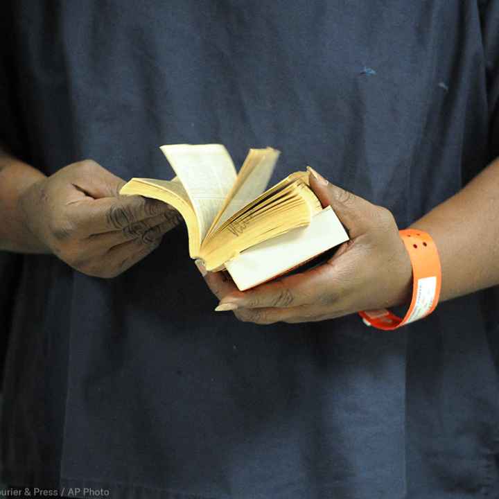 An incarcerated person thumbs through a book